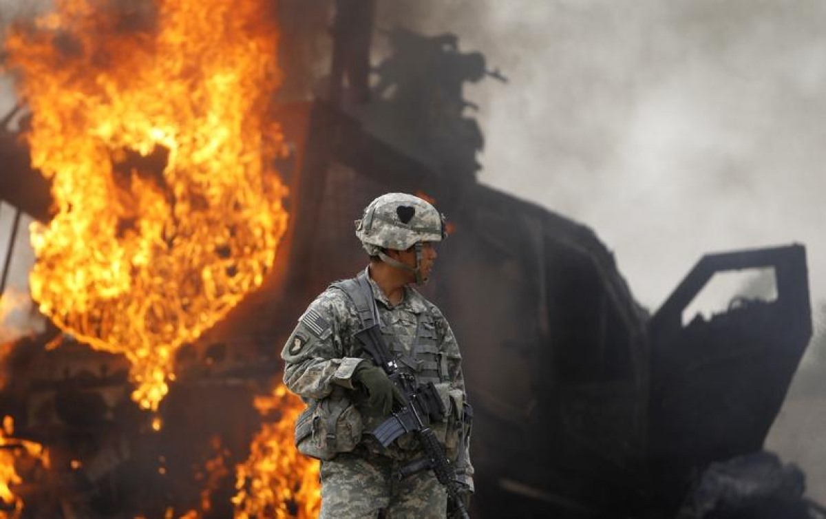 Đại úy Melvin Cabebe đứng gần một chiếc xe bọc thép đang bốc cháy sau khi nó va phải thiết bị nổ ở thung lũng Arghandab, phía bắc Kandahar, ngày 23/7/2010.