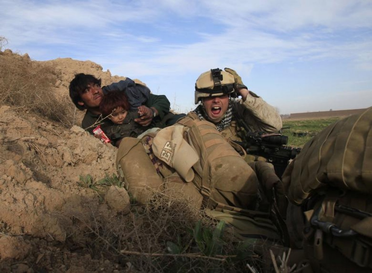 Chris Sanderson, một quân nhân Mỹ, đang cố gắng bảo vệ một người đàn ông và em nhỏ Afghanistan sau khi phiến quân Taliban nổ súng ở thị trấn Marjah, Nad Ali, tỉnh Helmand, ngày 13/2/2010.