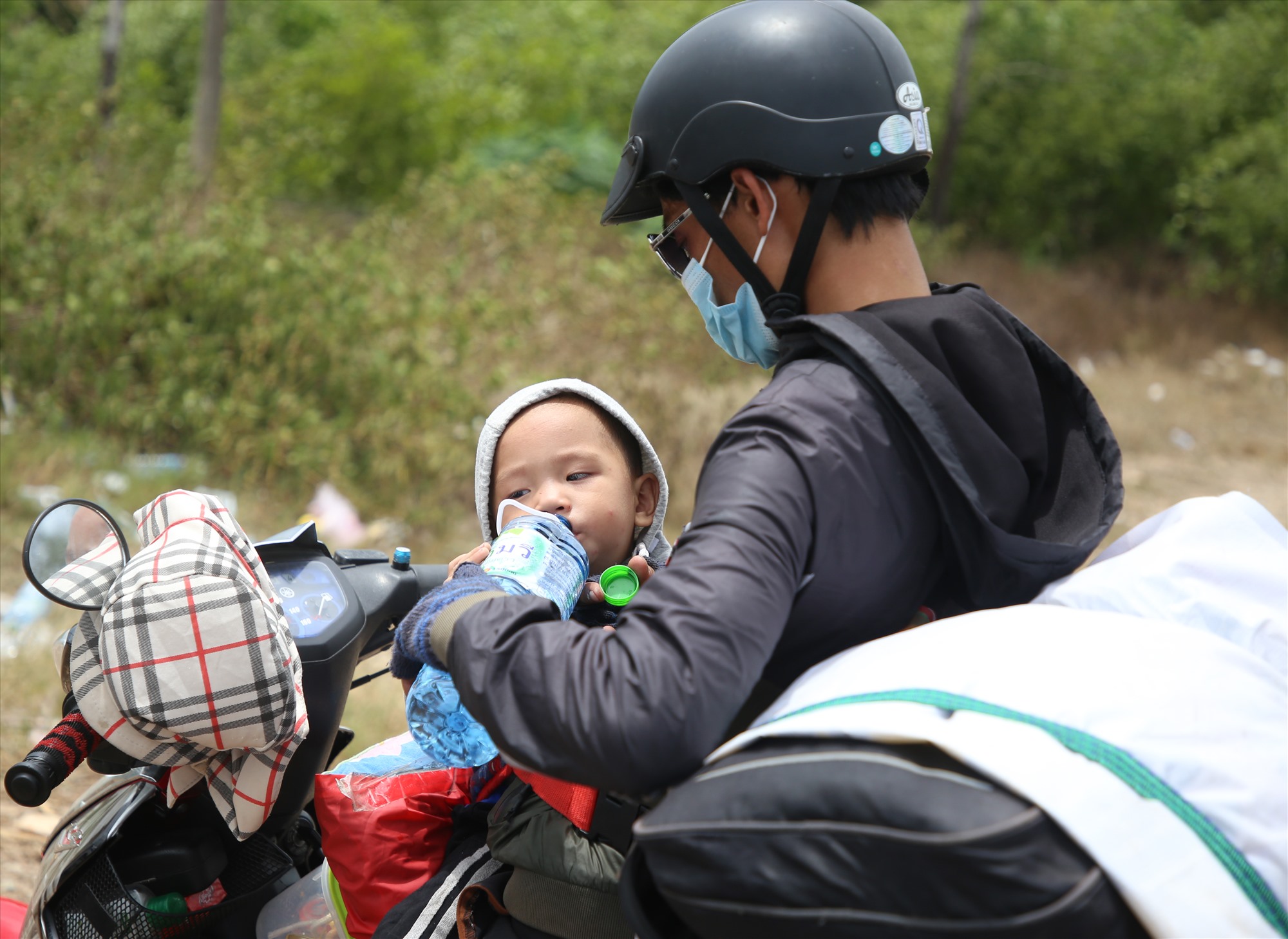 Anh Lê Văn Long, quê ở Nghệ An vội cho con trai 1,5 tuổi uống nước tại chốt trước khi tiếp tục lên đường về quê