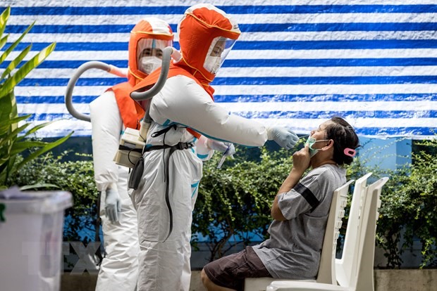 Nhân viên y tế trong trang phục bảo hộ lấy mẫu xét nghiệm COVID-19 cho người dân tại Bangkok, Thái Lan. (Ảnh: AFP/TTXVN)
