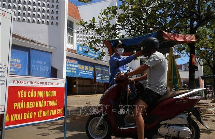 Bảo vệ chợ Đông Hà đo thân nhiệt cho người vào chợ. Ảnh: Hồ Cầu/TTXVN