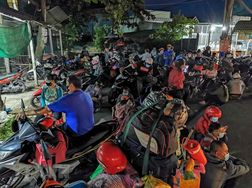 Người dân tập trung tại chốt kiểm soát dịch COVID-19 của tỉnh Hậu Giang trên Quốc lộ 1A tối 25/9 để chờ Cảnh sát giao thông dẫn đường đi qua địa bàn Hậu Giang. (Ảnh: Thanh Liêm/TTXVN)