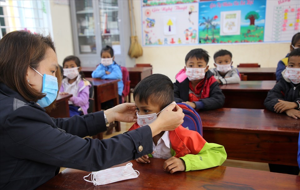 Giáo viên ở miền núi huyện Hướng Hóa hướng dẫn học sinh tiểu học đeo khẩu trang phòng dịch trong năm học 2020-2021. Ảnh: Hưng Thơ.
