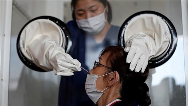 Nhân viên y tế lấy mẫu xét nghiệm COVID-19 cho người dân tại một trung tâm dã chiến ở Yokosuka, phía Nam Tokyo (Nhật Bản). (Ảnh: Reuters/TTXVN)