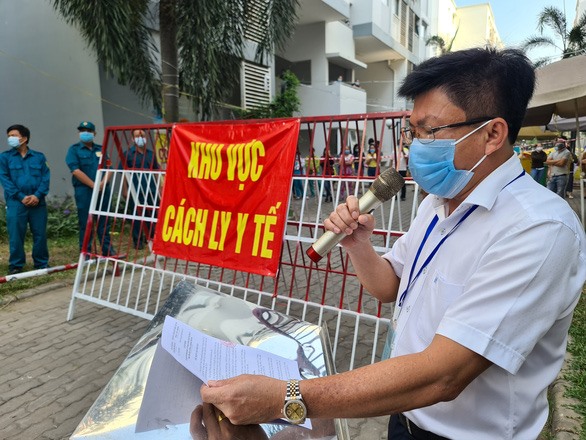 Ông Nguyễn Thanh Tâm - Chủ tịch UBND TP Thuận An (Bình Dương) đọc quyết định tháo dỡ phong tỏa tại một chung cư sau khi hoàn thành cách ly COVID-19 - Ảnh: tuoitre.vn