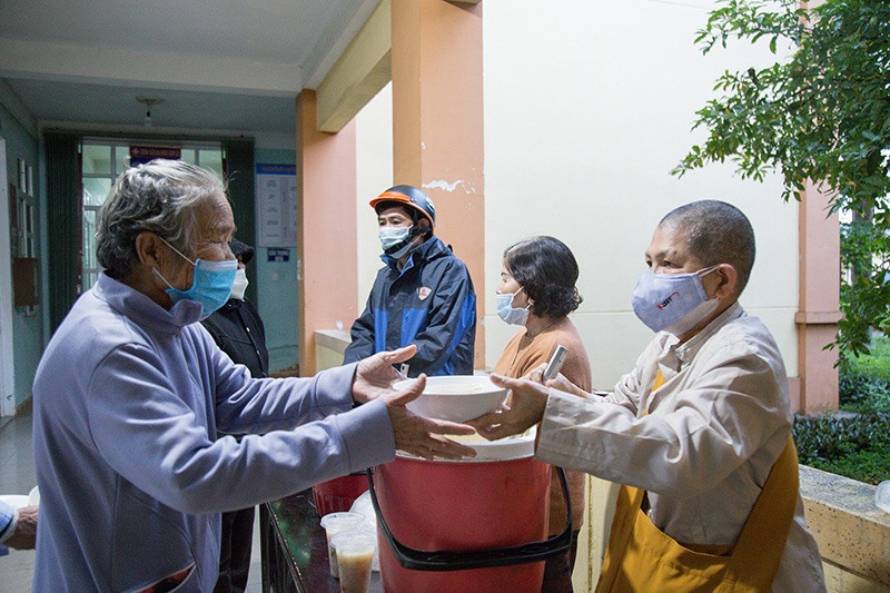 Sư cô Nguyệt Liên (bên phải) phát cháo dinh dưỡng cho các bệnh nhân nghèo tại Trung tâm Y tế huyện Cam Lộ - Ảnh: L.T