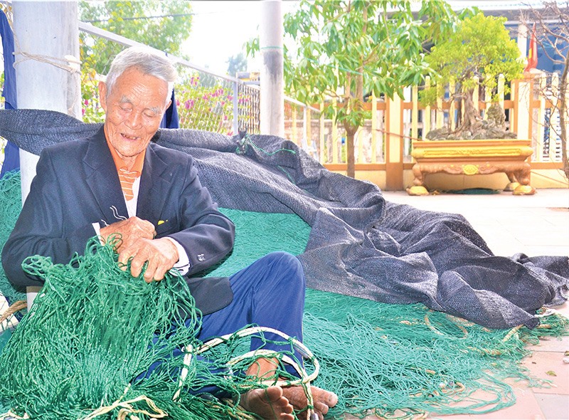 Lão ngư Nguyễn Văn Quýnh dù ở tuổi “gần đất, xa trời” vẫn giúp các con chuẩn bị lưới cho chuyến ra khơi - Ảnh: SỸ HOÀNG