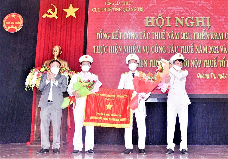 Phó Chủ tịch UBND tỉnh Lê Đức Tiến trao cờ “Đơn vị dẫn đầu phong trào thi đua năm 2021” của UBND tỉnh cho Cục Thuế tỉnh Quảng Trị - Ảnh: N.T.B
