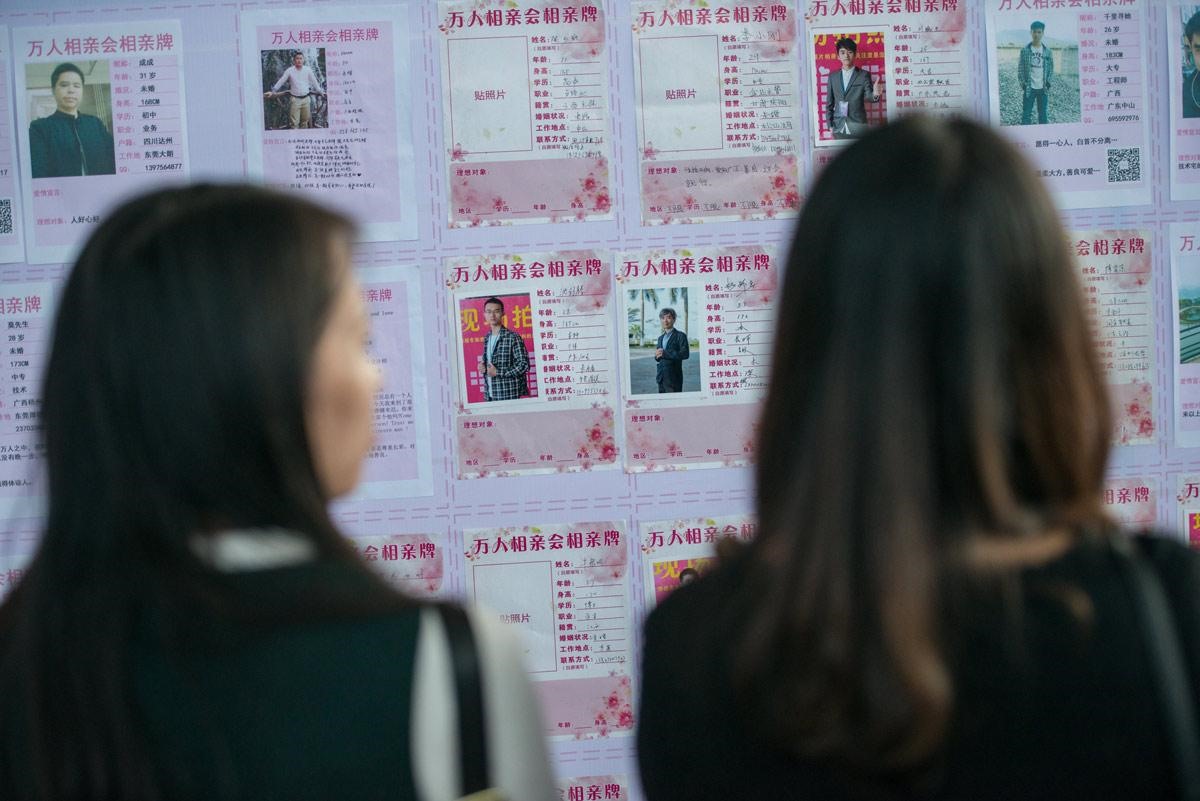 Phụ nữ trẻ Trung Quốc kiểm tra thông tin của các đối tượng nam giới khi tham dự sự kiện mai mối ở Đông Quan, tỉnh Quảng Đông năm 2017. Ảnh: Sixth Tone.