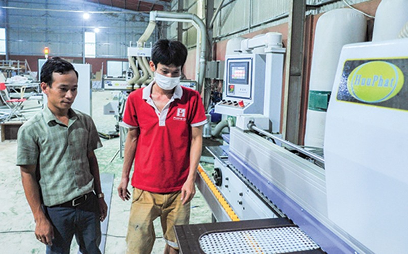 Anh Nguyễn Quốc Tuấn (bên trái) kiểm tra công nhân vận hành máy móc- Ảnh: T.T