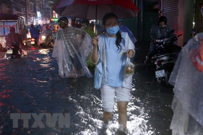 Người dân lội nước đi mua đồ ăn trên đường Hùng Vương. Ảnh: Trần Lê Lâm/TTXVN