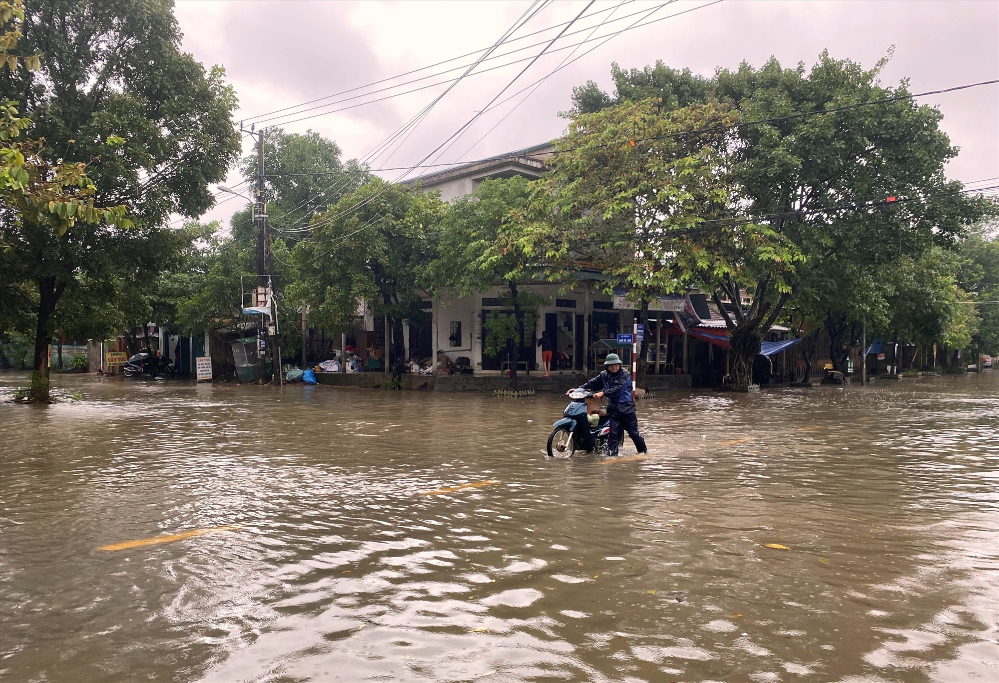 Người dân nhắc xe máy lội bộ qua đoạn nước ngập sâu trên đường Đặng Dung, Phường 2, TP. Đông Hà - Ảnh: N.B