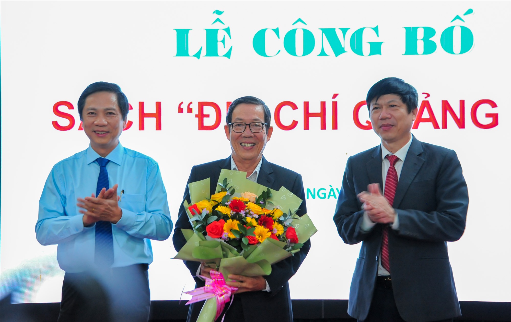 Phó Chủ tịch UBND tỉnh Hoàng Nam tặng hoa cho Tiến sĩ Nguyễn Bình, chủ biên sách Địa chí Quảng Trị, đại diện ban biên soạn - Ảnh: Trần Tuyền