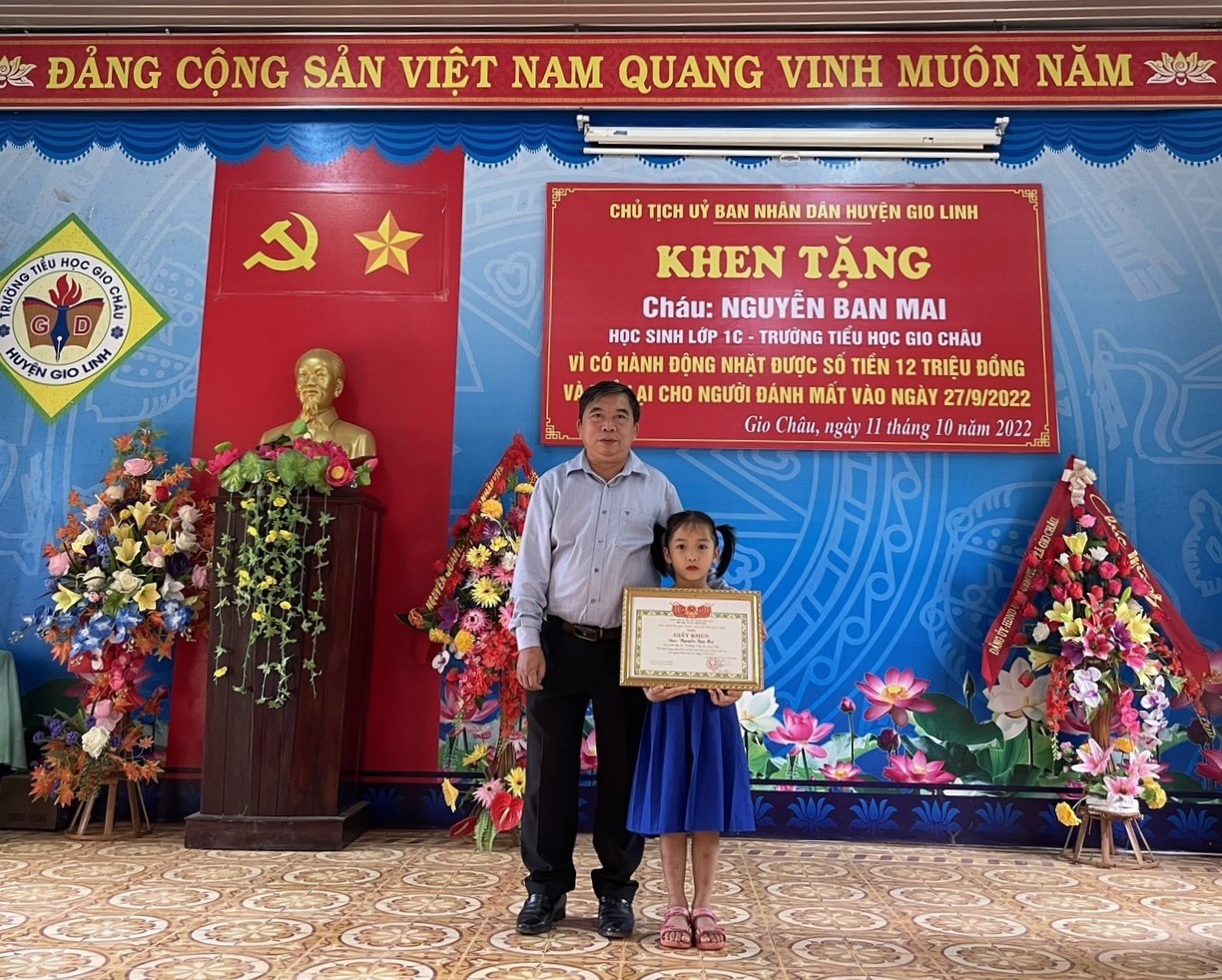 Trao giấy khen của UBND huyện cho em Nguyễn Ban Mai vì có hành động đẹp nhặt của rơi trả lại người mất - Ảnh: CTV