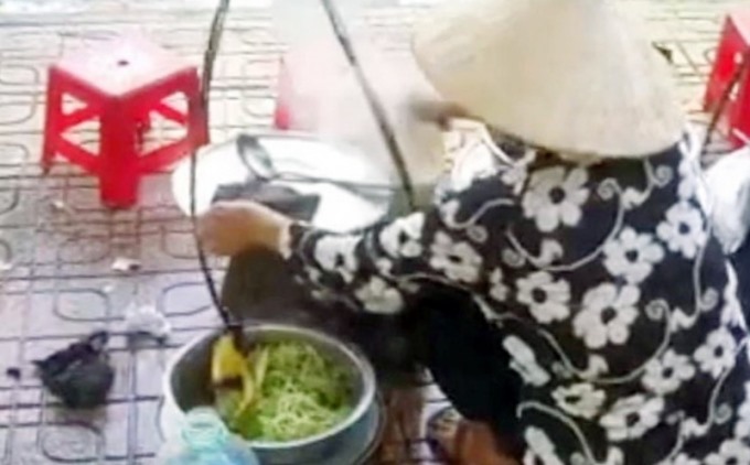 Hình ảnh bà H.T.T. đổ thức ăn thừa vào nồi nước lèo lan truyền trên mạng. Ảnh chụp lại clip.