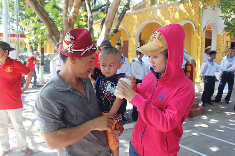 Vợ chồng anh Nguyễn Đức Nhân và chị Lê Thị Thu cùng con trai vui mừng đón người dân ở đất liền ra thăm đảo Sinh Tồn -Ảnh: M.H