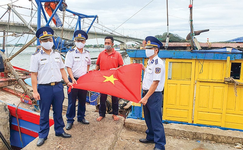Cán bộ, chiến sĩ Hải đội 202, Bộ Tư lệnh Vùng Cảnh sát biển 2 tặng cờ Tổ quốc cho ngư dân - Ảnh: L.A
