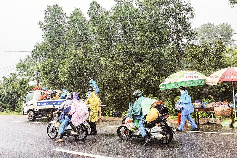 Cán bộ, chiến sĩ Công an tỉnh đội mưa hỗ trợ người dân về quê tránh dịch - Ảnh: TL