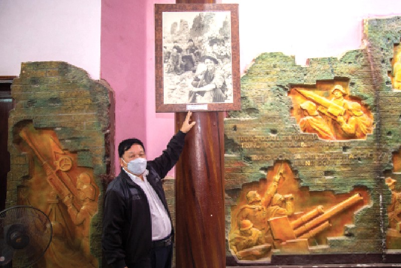 Ông Trần Khánh Khư bên bức ảnh “Nụ cười thách thức bom đạn” -Ảnh: HOÀNG TÁO