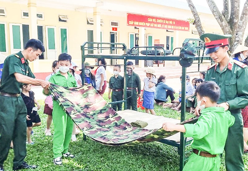 Học sinh Trường Tiểu học thị trấn Cam Lộ trải nghiệm việc gấp chăn màn tại Trung đoàn 19 -Ảnh: T.L