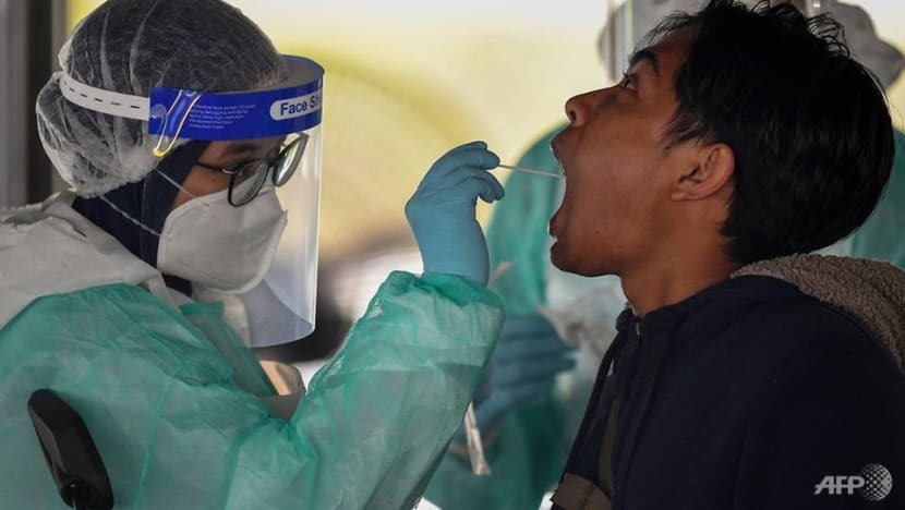 Một nhân viên y tế ở Malaysia dùng tăm bông để lấy mẫu xét nghiệm COVID-19 từ một người đàn ông. Ảnh: AFP