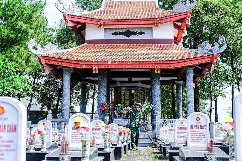 Anh Nguyễn Thế Lâm chăm sóc các phần mộ liệt sĩ tại Nghĩa trang liệt sĩ quốc gia Đường 9 - Ảnh: T.T