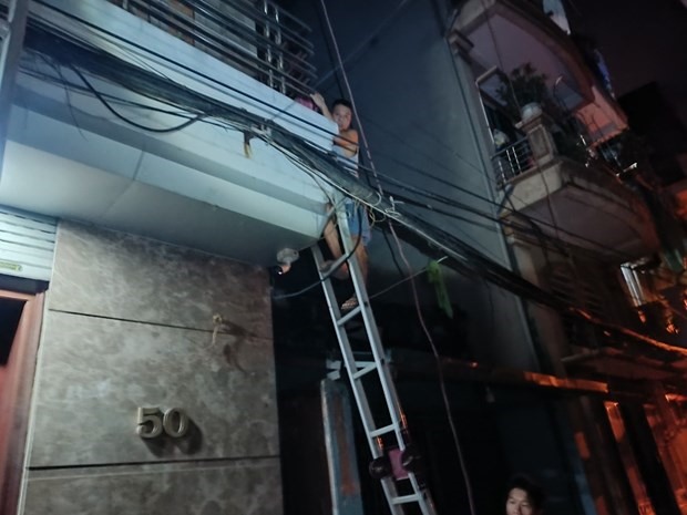 Đưa gia đình ông Hưng thoát xuống bằng thang chuyên dụng. (Nguồn: Thanh niên)