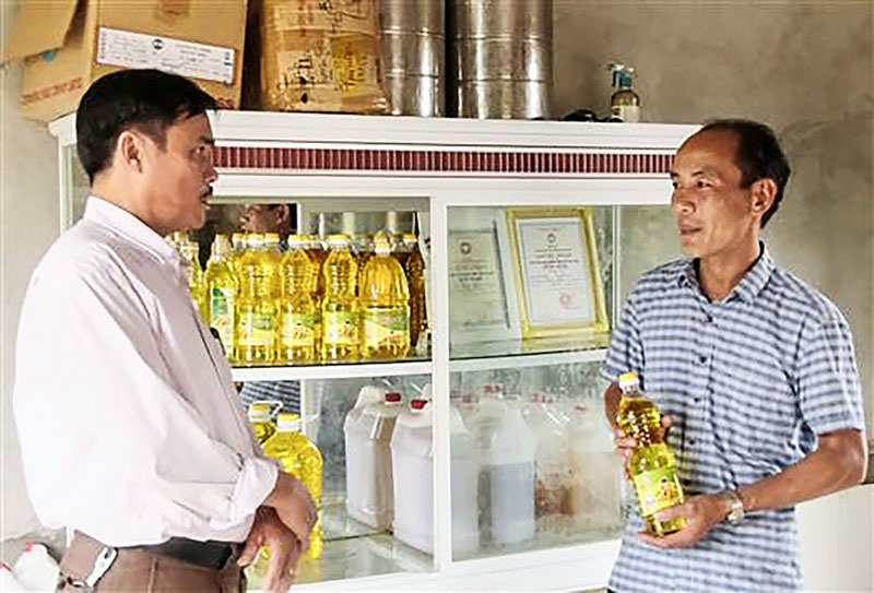 Anh Lê Thanh Biên (bên phải) và sản phẩm dầu lạc Làng An - Ảnh: P.N