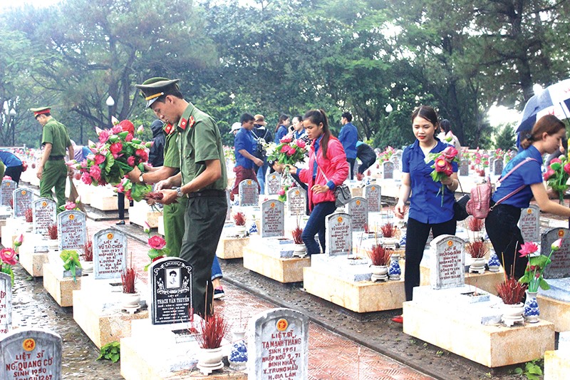 Đoàn viên thanh niên chăm sóc các phần mộ liệt sĩ tại Nghĩa trang Liệt sĩ quốc gia Trường Sơn - Ảnh: HUY NAM
