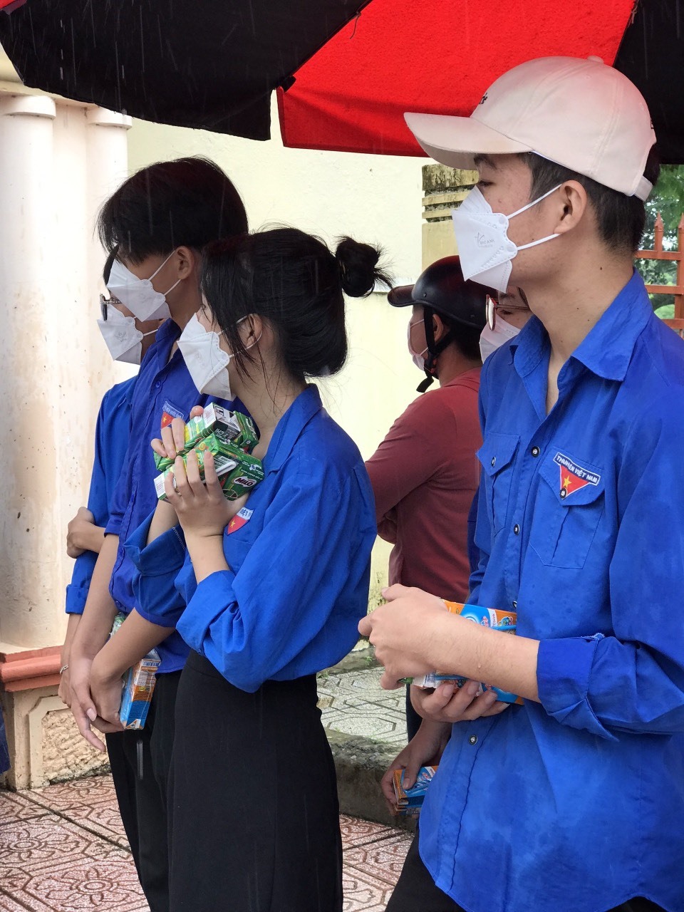 Hình ảnh các đoàn viên thanh niên thị trấn Lao Bảo, kịp thời hỗ trợ sữa, nước lọc và áo mưa cho thí sinh rời phòng thi trong cơn mưa nặng hạt