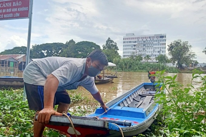 Anh Lê Bình Hổ bên chiếc vỏ lãi dũng cảm cứu hàng chục người Việt đang sắp đuối nước giữa dòng nước xiết. Nguồn: Dân trí