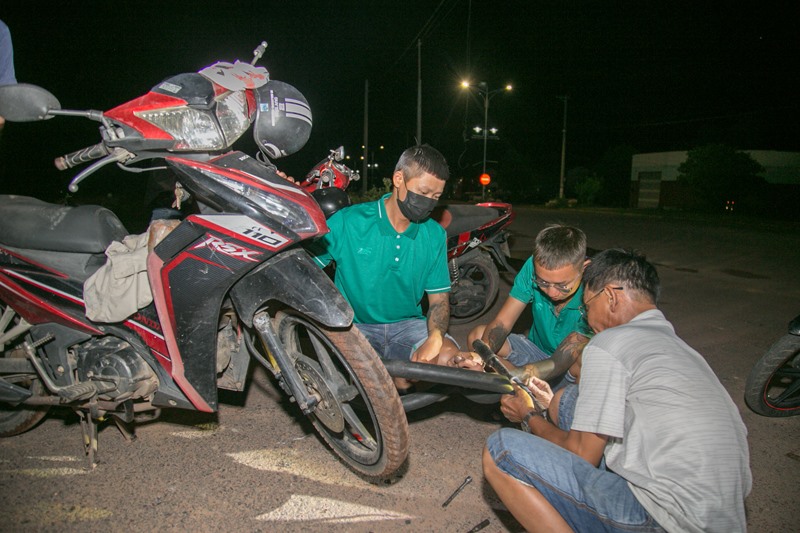 Đội SOS Đông Hà hỗ trợ sửa xe máy của anh Nguyễn Văn Sách bị thủng săm - Ảnh: LÊ TRƯỜNG