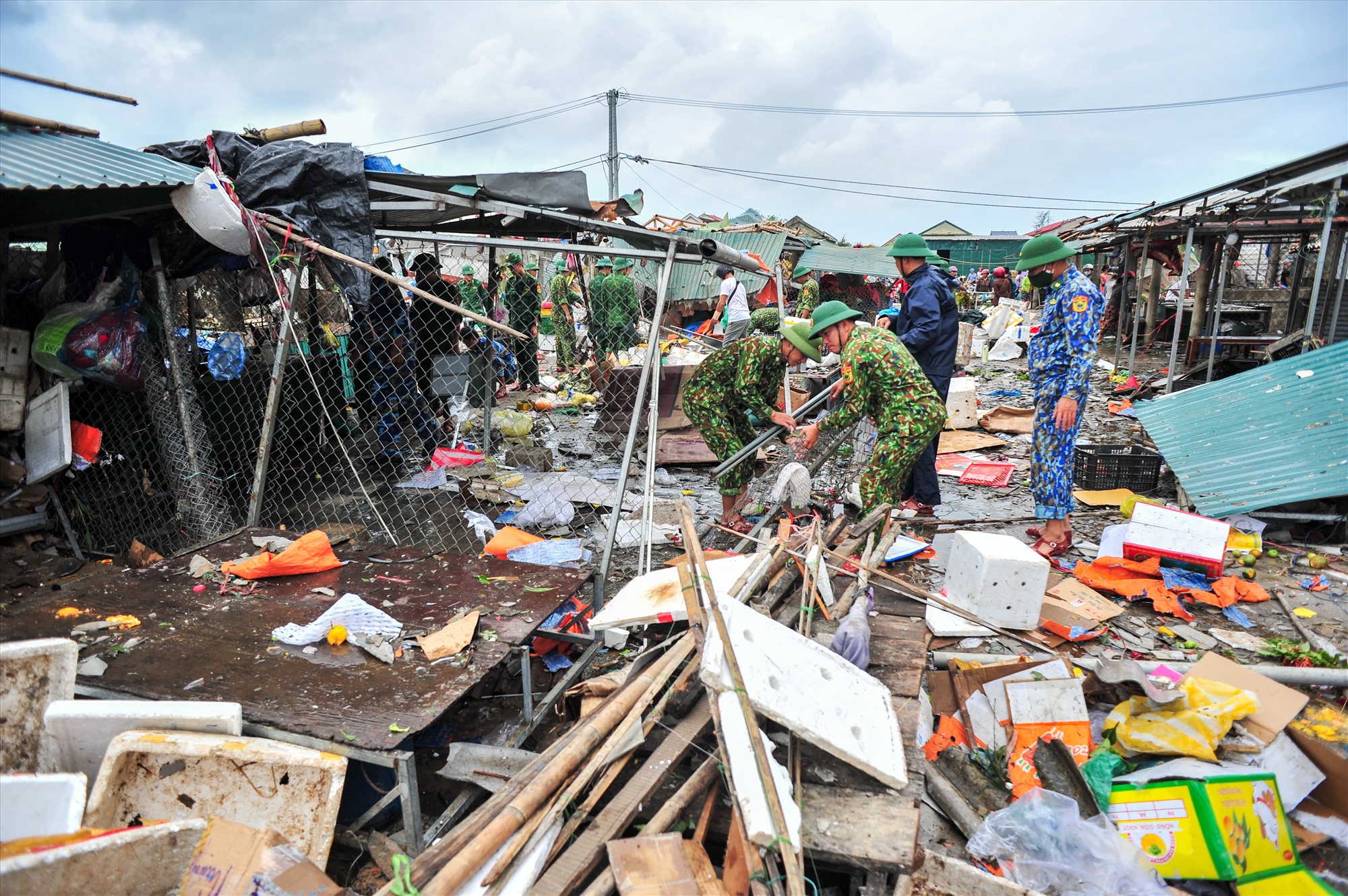 Lực lượng chức năng giúp người dân dọn dẹp vệ sinh, dựng lại lều quán  – Ảnh: Trần Tuyền