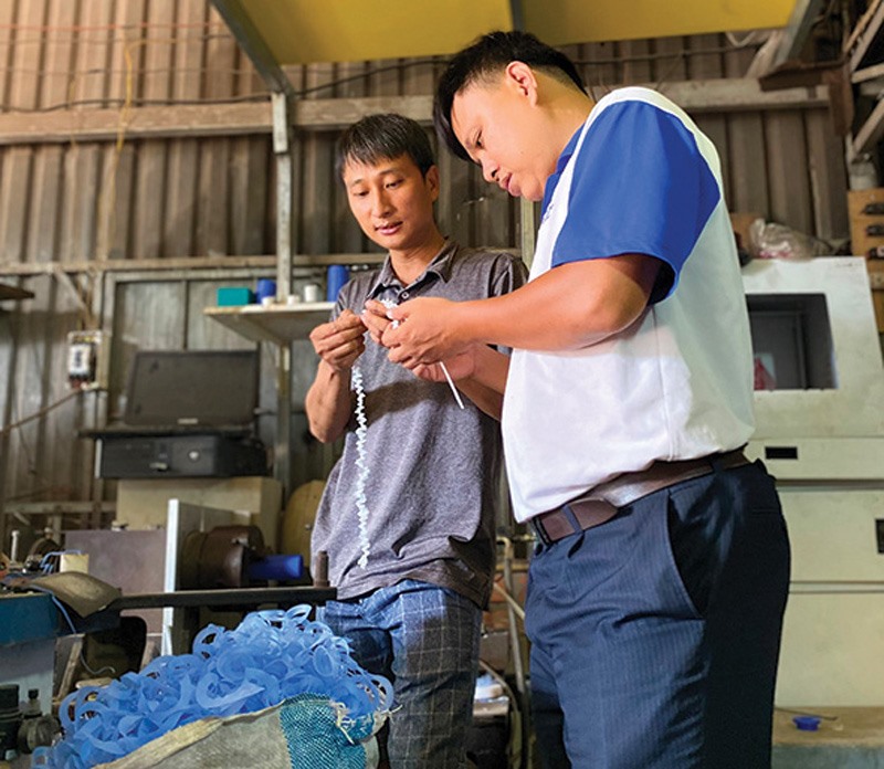 Anh Trần Thái Sơn (bên phải)cùng nhân viên chế tạo một chi tiết trong máy lọc nước -Ảnh:T.P