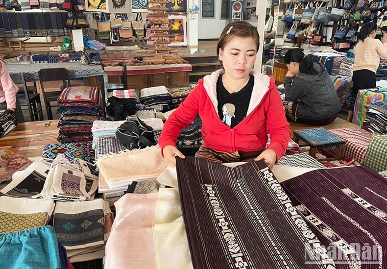 Giới thiệu sản phẩm vải dệt thủ công của Lào cho du khách. (Ảnh: Hải Tiến)