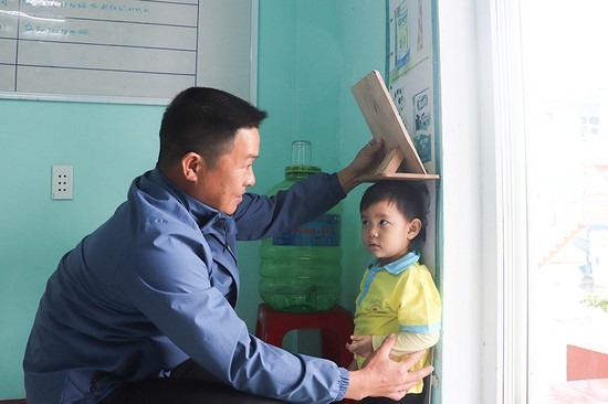 Công việc thường ngày của anh Bảy là chăm sóc sức khỏe cho trẻ tại Trường Mầm non Vĩnh Thái - Ảnh: TP