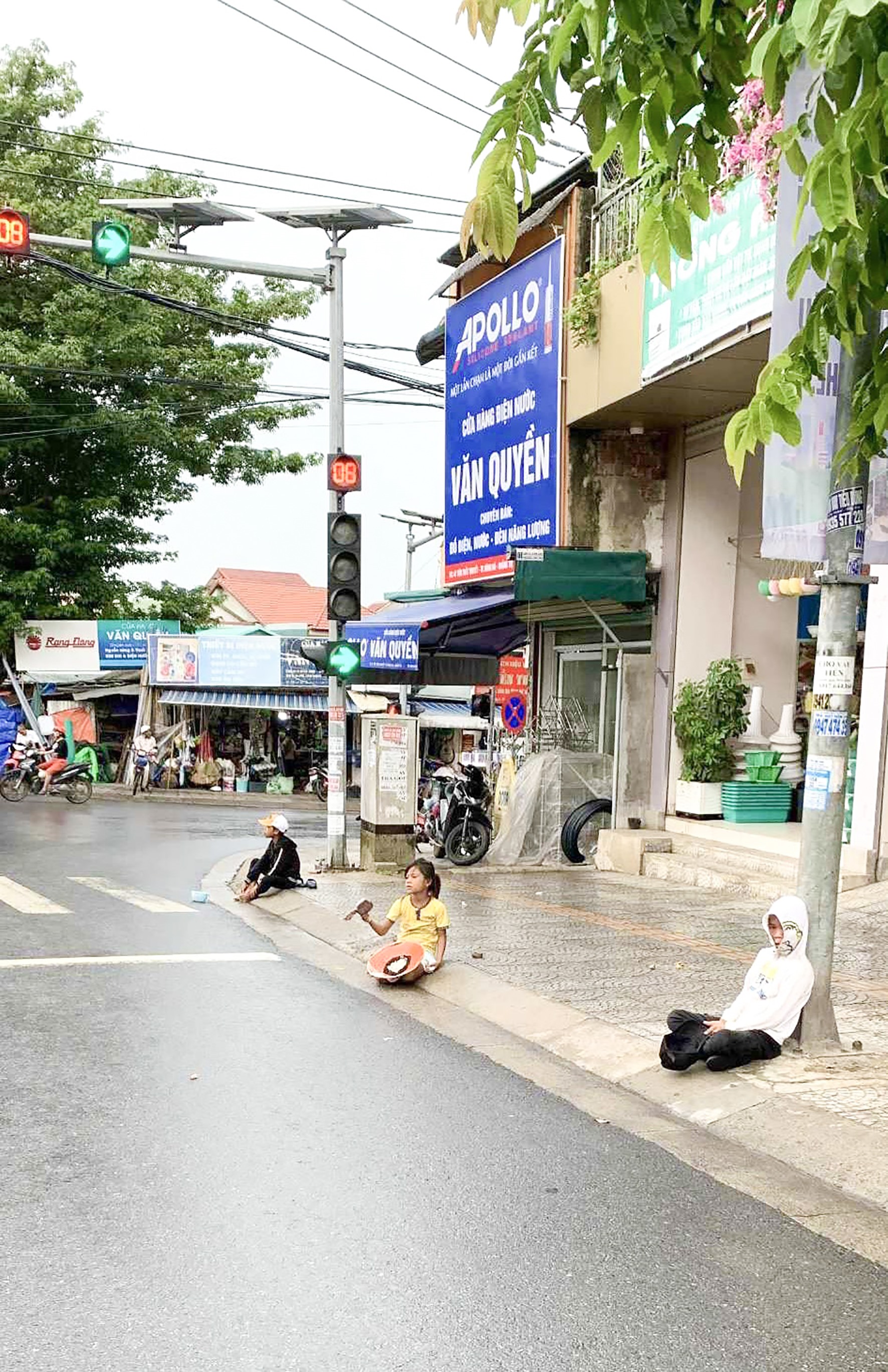 Nhiều người lớn và trẻ em xin ăn ngồi ngay cột đèn giao thông trên các tuyến đường của TP. Đông Hà -Ảnh: M.Đ
