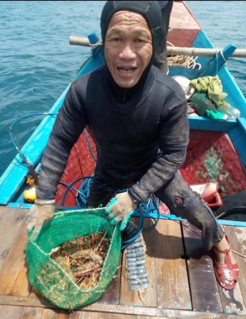 Thợ lặn Lê Sơn Đông đưa thủy sản từ dưới biển lên thuyền - Ảnh: NVCC
