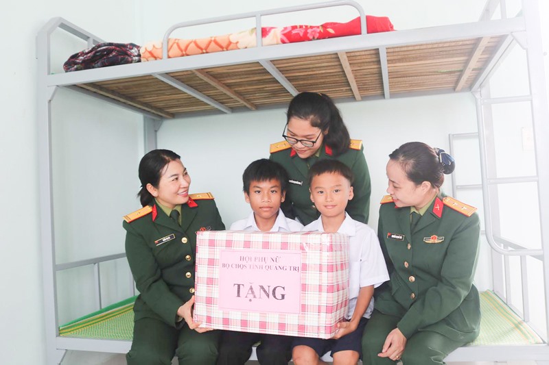 Thiếu tá Trần Thị Hà (ngoài cùng bên trái) cùng chị em phụ nữ Bộ CHQS tỉnh tặng quà cho các cháu có hoàn cảnh khó khăn tại Trung tâm Điều dưỡng người có công và Bảo trợ xã hội tỉnh Quảng Trị -Ảnh: H.T