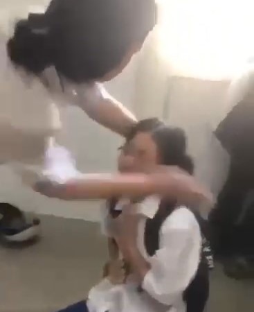 Theo clip, 1 học sinh nữ bị một số bạn nữ liên tục chửi thề, tát, dùng mũ bảo hiểm đánh vào mặt - Ảnh: Cắt từ clip