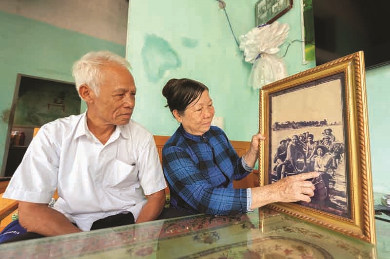 Bà Nguyễn Thị Thu cùng chồng xem lại bức ảnh “Cha con lão ngư dân Triệu Phong chở bộ đội và vũ khí tiếp sức Thành Cổ” - Ảnh: TRẦN TUYỀN