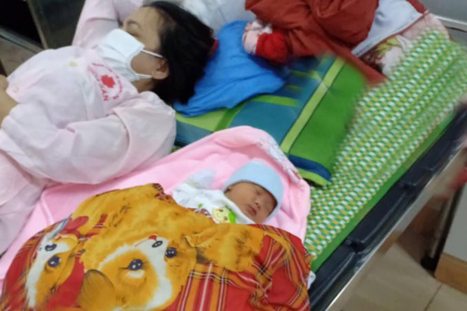 Con trai sơ sinh của sản phụ Thò Ý Dũng ngủ ngon lành bên mẹ ở Trung tâm Y tế huyện Hải Lăng. Ảnh: Ngô Tuấn