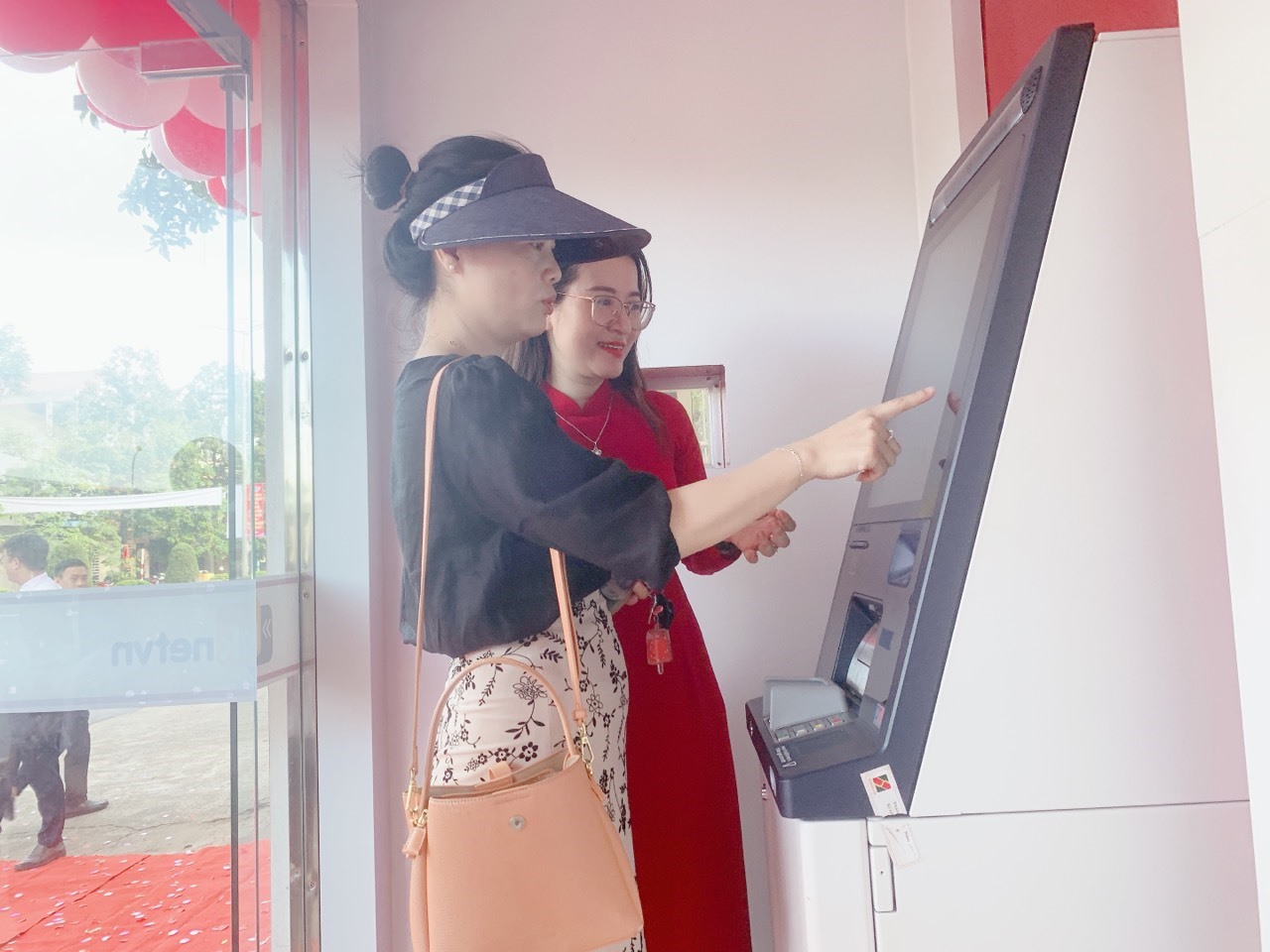 Nhân viên Agribank chi nhánh TP. Đông Hà hướng dẫn khách hàng trải nghiệm dịch vụ tại máy gửi, rút tiền tự động CDM - Ảnh: H.T