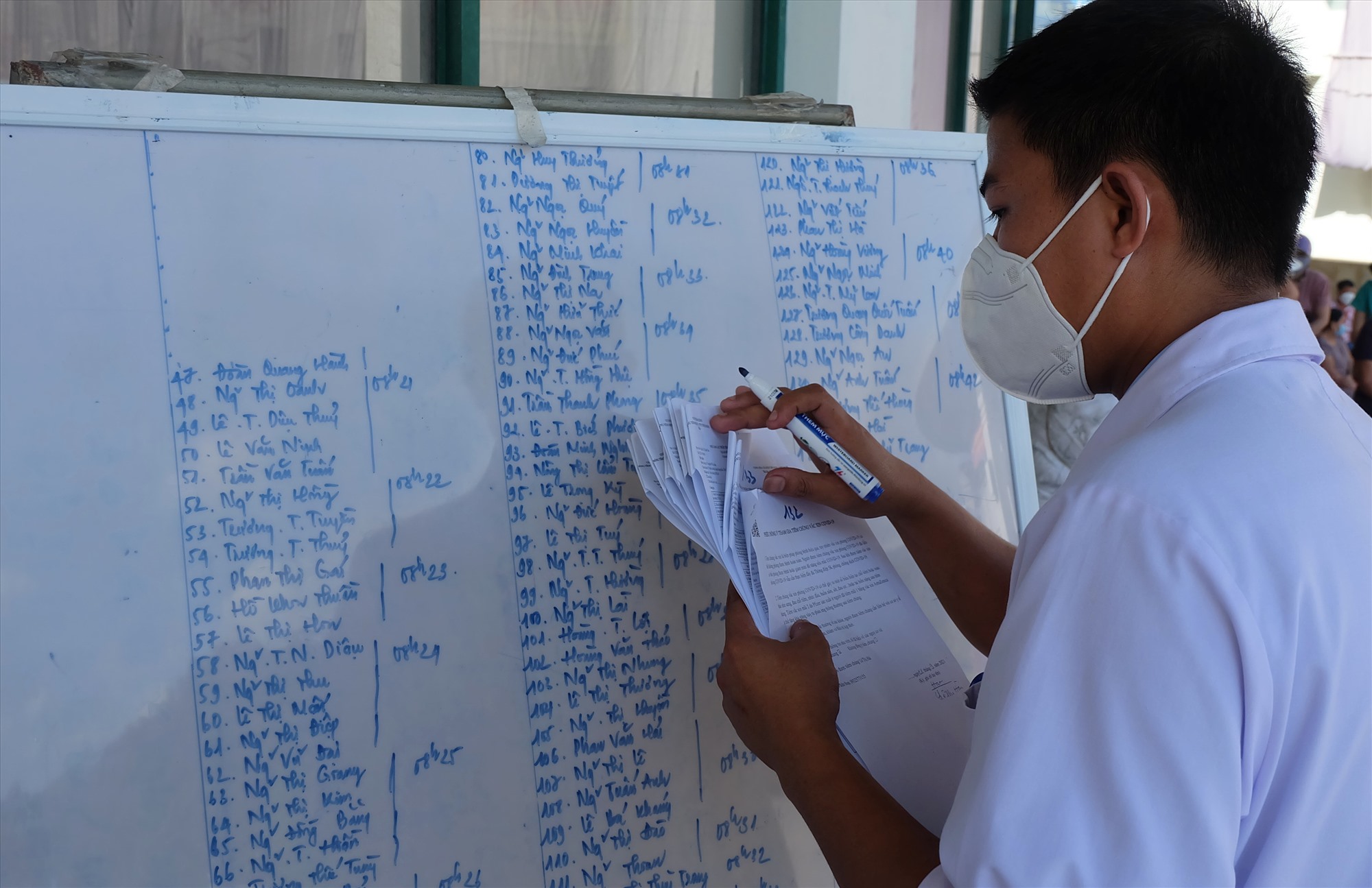 Y sĩ Nguyễn Đăng Thông ghi danh sách người được tiêm chủng lên bảng. Ảnh: hưng Thơ-Nhật Minh