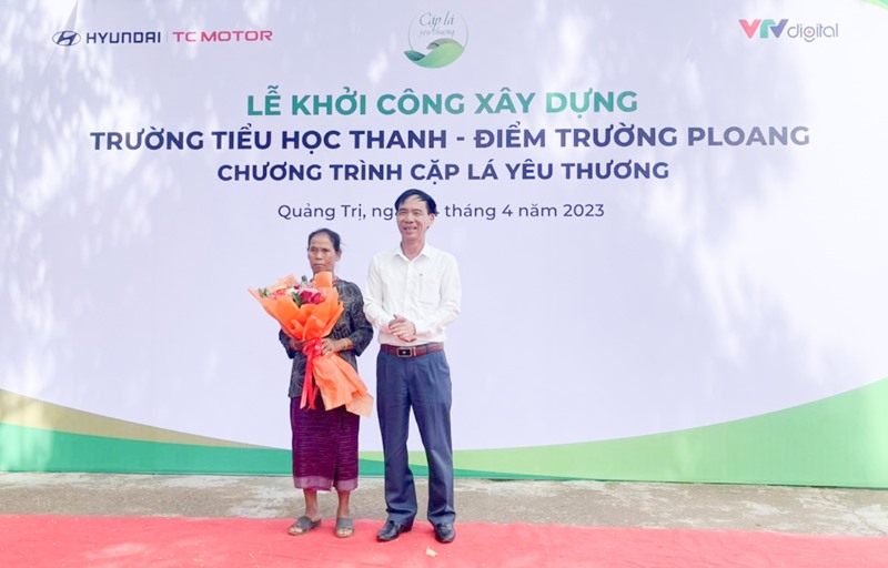 Lãnh đạo UBND huyện Hướng Hóa tặng hoa biểu dương gia đình bà Nuông đã hiến đất vì lợi ích của cộng đồng - Ảnh: M.L