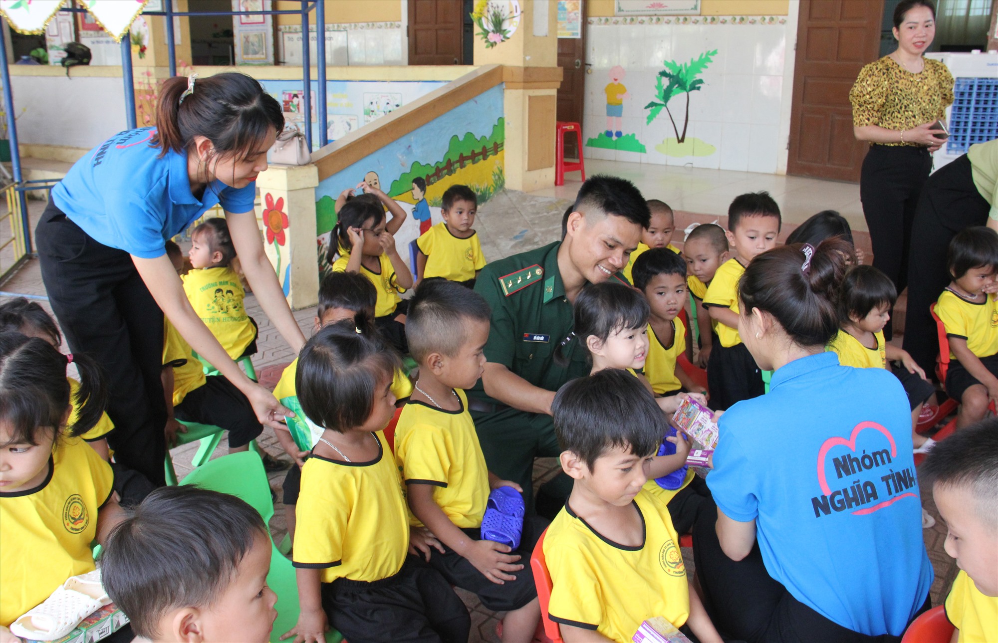 ! Đại uý Hồ Văn Hữu cùng với các cô giáo đang trao quà cho các cháu ở trường Mầm non xã A Dơi - Ảnh HỒ THANH THOAN (1)