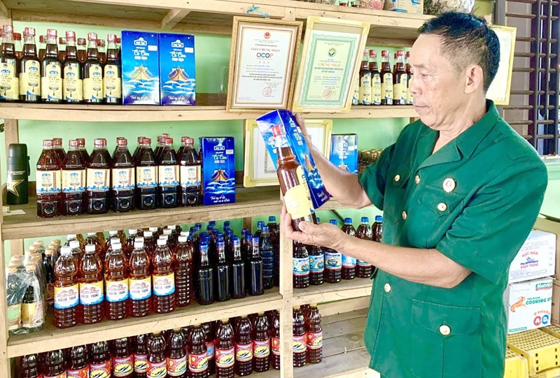Cựu chiến binh Bùi Xuân Khiêm và những sản phẩm nước mắm truyền thống do mình sản xuất -Ảnh: P.N