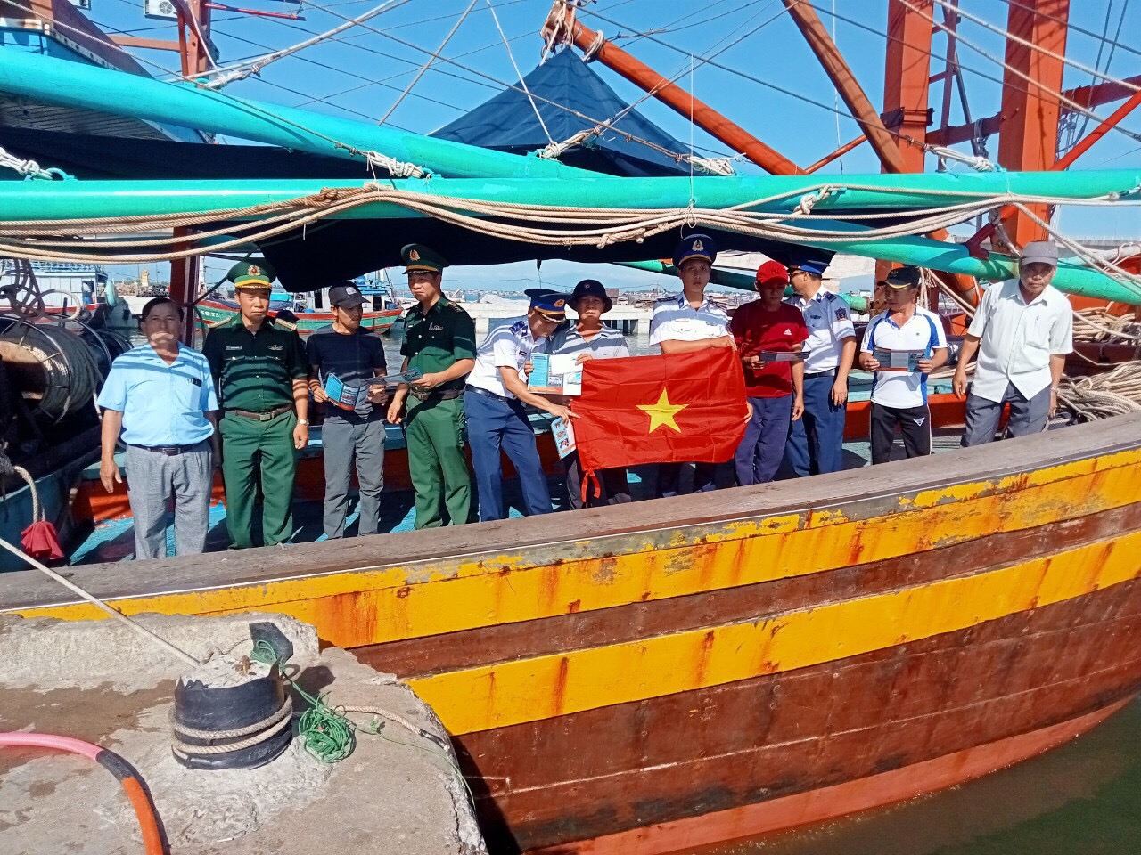 Cán bộ,chiến sĩ Đồn Biên phòng Triệu Vân phối hợp với Cảnh sát biển tuyên truyền và tặng cờ cho bà con ngư dân trên tàu.