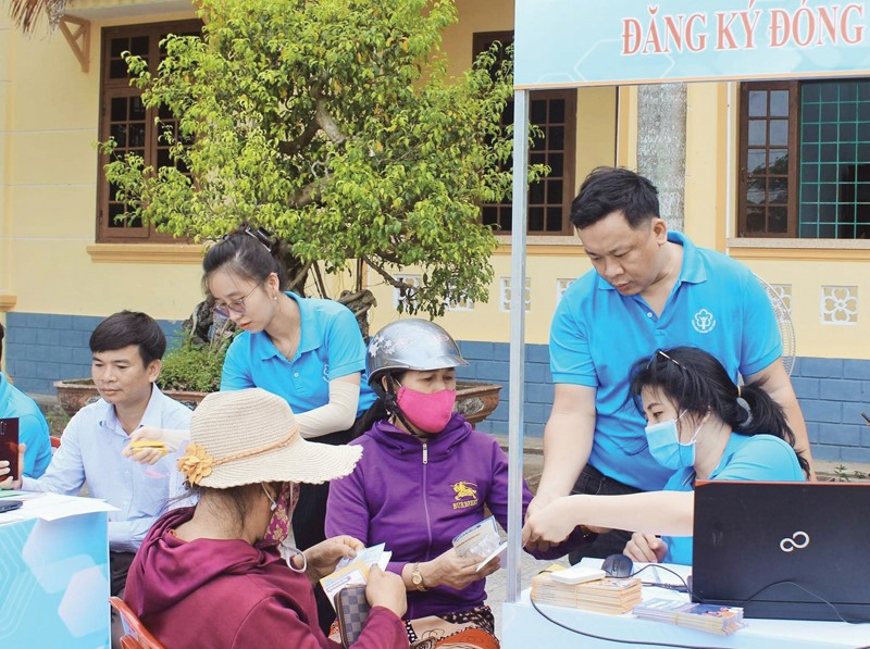 Đoàn viên CĐCS BHXH tỉnh hướng dẫn người dân huyện Triệu Phong đăng ký cài đặt ứng dụng VssID-Bảo hiểm xã hội số - Ảnh: Q.H