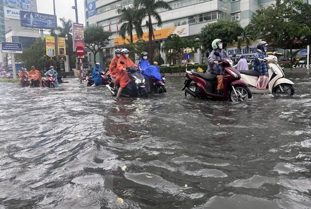 Đường Nguyễn Văn Linh ngập sâu trong nước, người dân phải dắt bộ phương tiện. (Ảnh: Trần Lê Lâm/TTXVN)